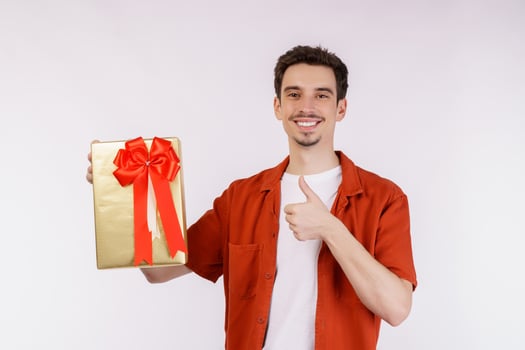 Portrait of Happy young caucasian man showing present box and looking at camera isolated over white background photo