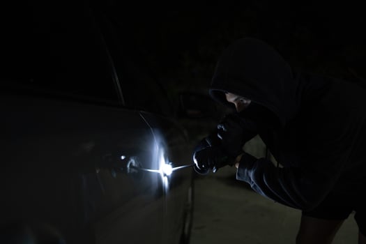 Man in black trying to steal a car. Car theft concept. photo
