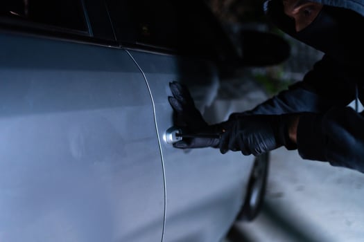 Car thief using a tool to break into a car photo