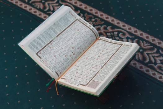 a close up of the holy book Al-Quran on a green prayer rug. Islamic photo concept.