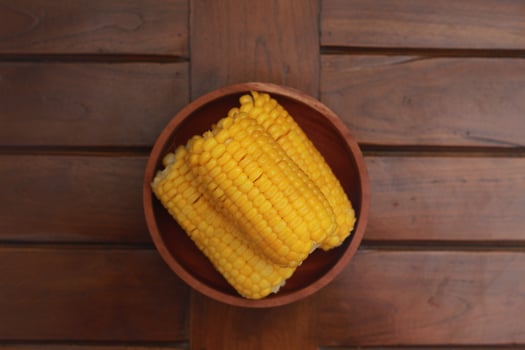 a close up of corn on the cob served in a wooden bowl. photo