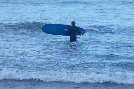 Surfers getting ready to enter the water and walking with the board along the shore. photo