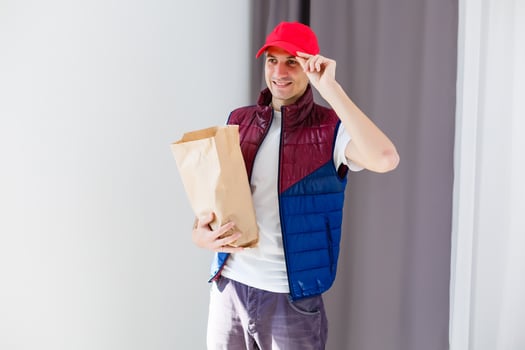 Paper pocket and food containers in hands of a smiling deliveryman. Quality service of a restaurant. photo
