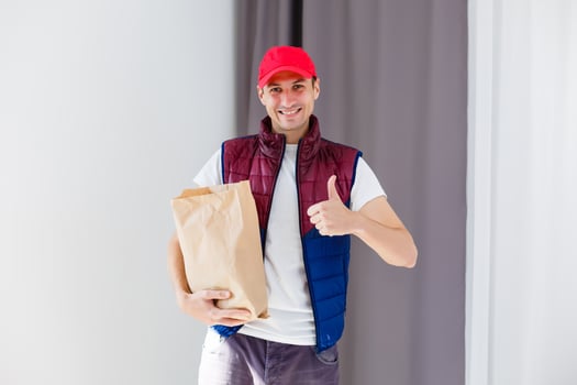 Paper pocket and food containers in hands of a smiling deliveryman. Quality service of a restaurant. photo
