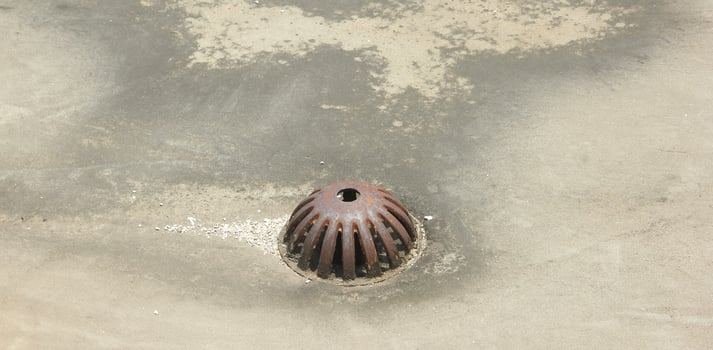 Old rustic water drain with metal iron material on roof top isolated on concrete flooring. photo