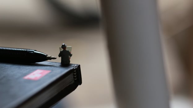 a view of miniature figure reading a newspaper on a book. photo