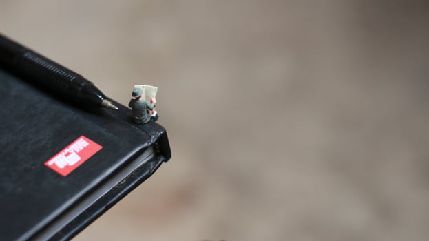 a view of miniature figure reading a newspaper on a book. photo
