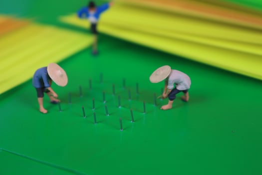 miniature figure of farmers growing crops in the form of staples on green paper. Concept of agriculture photo. photo