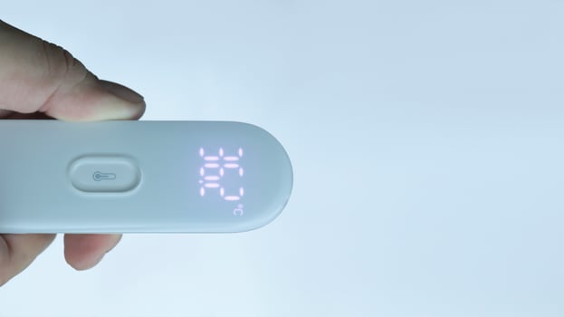 A hand holding digital thermometer showing normal temperature with isolated on white. photo