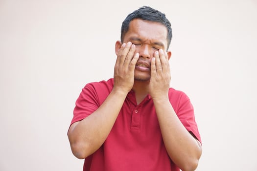 Asian man has eyestrain from looking at the computer photo