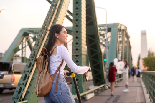 Portrait of young beautiful woman with an electric scooter  over bridge in modern city  background photo