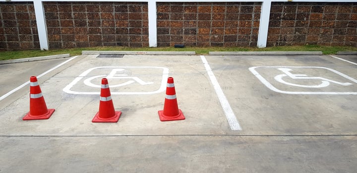 Three orange traffic cone on street for reservation parking of disabled people with brown brick wall background. Symbol, Restrict area and Service photo
