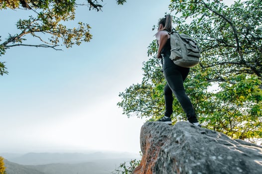 Young hiker woman standing on rocky and looking view photo