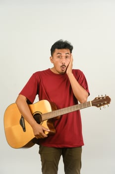Portrait of Young Asian man in red t-shirt playing an acoustic guitar isolated on white background photo