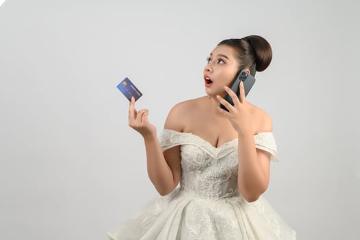 Young asian beautiful bride posting with credit card and smartphone in hand photo