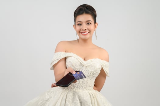 Young asian beautiful bride posting with credit card and smartphone in hand photo