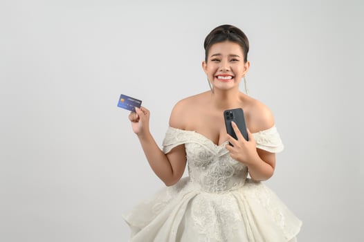 Young asian beautiful bride posting with credit card and smartphone in hand photo
