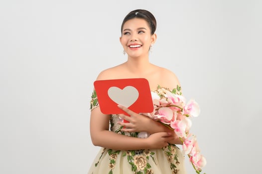 Asian beautiful bride smiling and posing with heart sign on white background photo