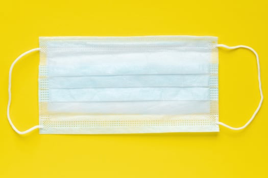Medical surgical face mask on yellow background. World pandemic insurance, airborne diseases, influenza, SARS photo