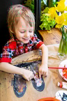 boy drawing the ears of a handmade Easter bunny made of cardboard. Preparation for the celebration of the Easter holiday. photo