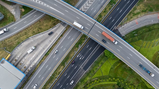 Aerial top view of highway junction interchange road. Drone view of the elevated road, traffic junctions, and green garden. Transport trucks and cars driving on highway. Infrastructure in modern city. photo
