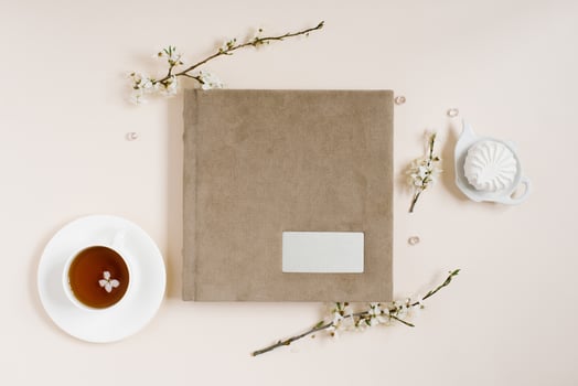 Beige family or wedding photo album with apple flowers and cup of tea and marshmallow