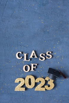 Graduated 2023 concept. Class of 2023 text with graduate cap on dark background with bokeh photo