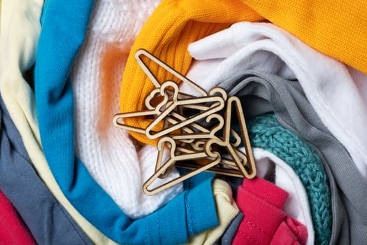 Mini hangers on colorful clothes  top view. Second hand, clothing donation and recycling concept photo