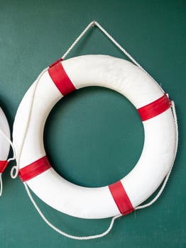 Closeup of the white lifebuoy is hanging on the green wall. photo