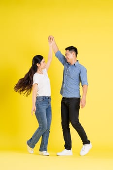 full body image of asian couple posing on yellow background photo