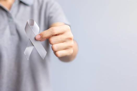 Brain Cancer Awareness month, woman hand holding grey color Ribbon for supporting people life. Healthcare and World cancer day concept photo
