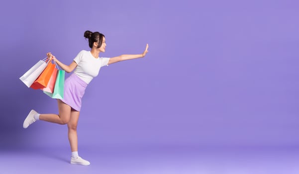 Young Asian woman holding shopping bag on purple background photo