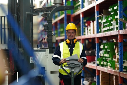 A worker in a warehouse with a forklift photo
