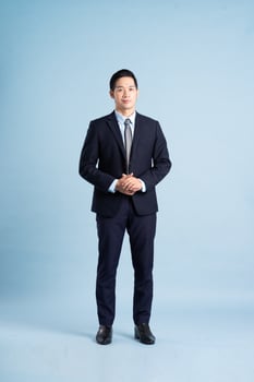 portrait of asian businessman wearing suit on blue background photo