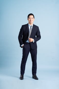 portrait of asian businessman wearing suit on blue background photo