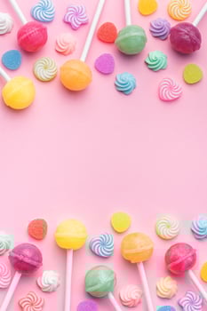 Sweet lollipops and candies on pink background photo