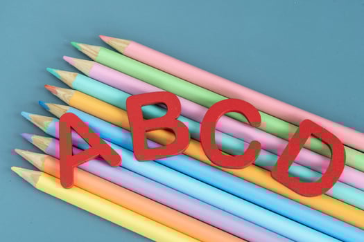 Back to school concept with assorted letters and colored pencils in pastel colors photo