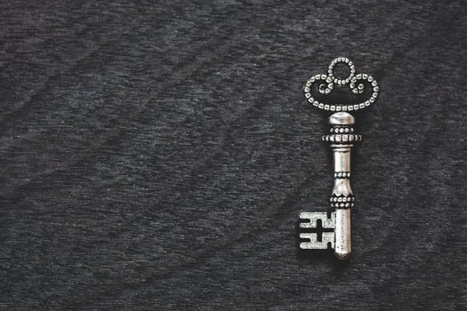 Single vintage silver key on old wooden background, copy space photo