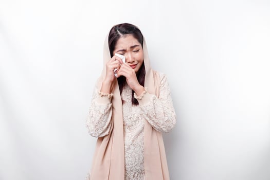 An unhappy Asian Muslim woman wearing a headscarf is wiping her tears in despair, feeling depressed and lonely. photo