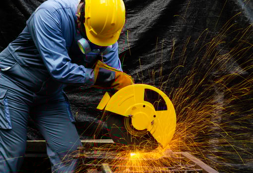 Worker cuts metal by electric circular saw. Fountain of grinding metal sparks. Metal working with personnel protective equipment. photo