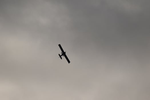 Small plane flying in the sky against dark clouds photo