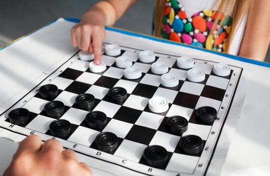 Baby hands child plays with an adult a board game of checkers. photo