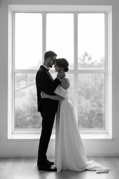 groom in a black suit tie and the bride in a bright studio photo