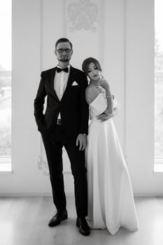 groom in a black suit tie and the bride in a bright studio photo