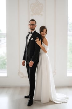 groom in a black suit tie and the bride in a bright studio photo