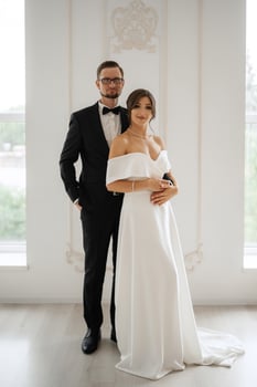 groom in a black suit tie and the bride in a bright studio photo