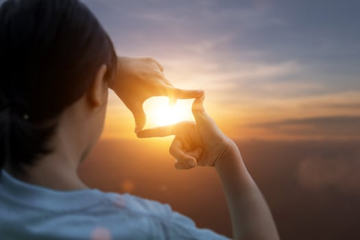 Child girl making frame around the sun with her hands capturing in the sunrise. Planning and vision concept photo