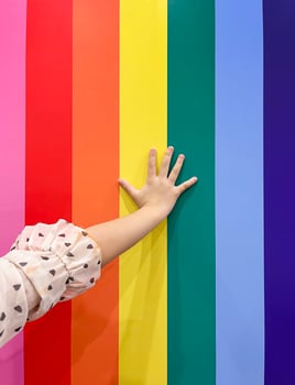 Child hand put on rainbow LGBT flag background. concept for LGBTQ equality movement community. photo