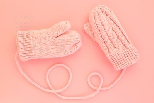 Close-up pink mittens and shaped of string on pink background. Lifestyle and warm feelings concept. Valentine day. Monocolor romantic pattern. Winter theme. Flat lay composition. Top view. Copy space photo