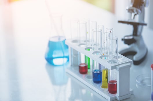 Microscope and colorful test tubes on table in Laboratory. Science chemistry concept. Blue tone photo